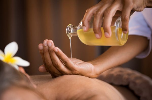 Closeup of masseur hands pouring aroma oil on woman back. Masseuse prepare to do oriental spa procedure for relaxing treatment. Therapist doing aromatherapy oil massage on woman body.